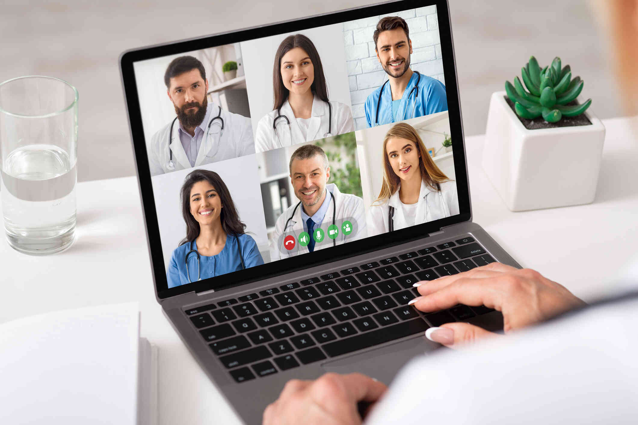 A woman looks at her computer while speaking to a group of people through her screen