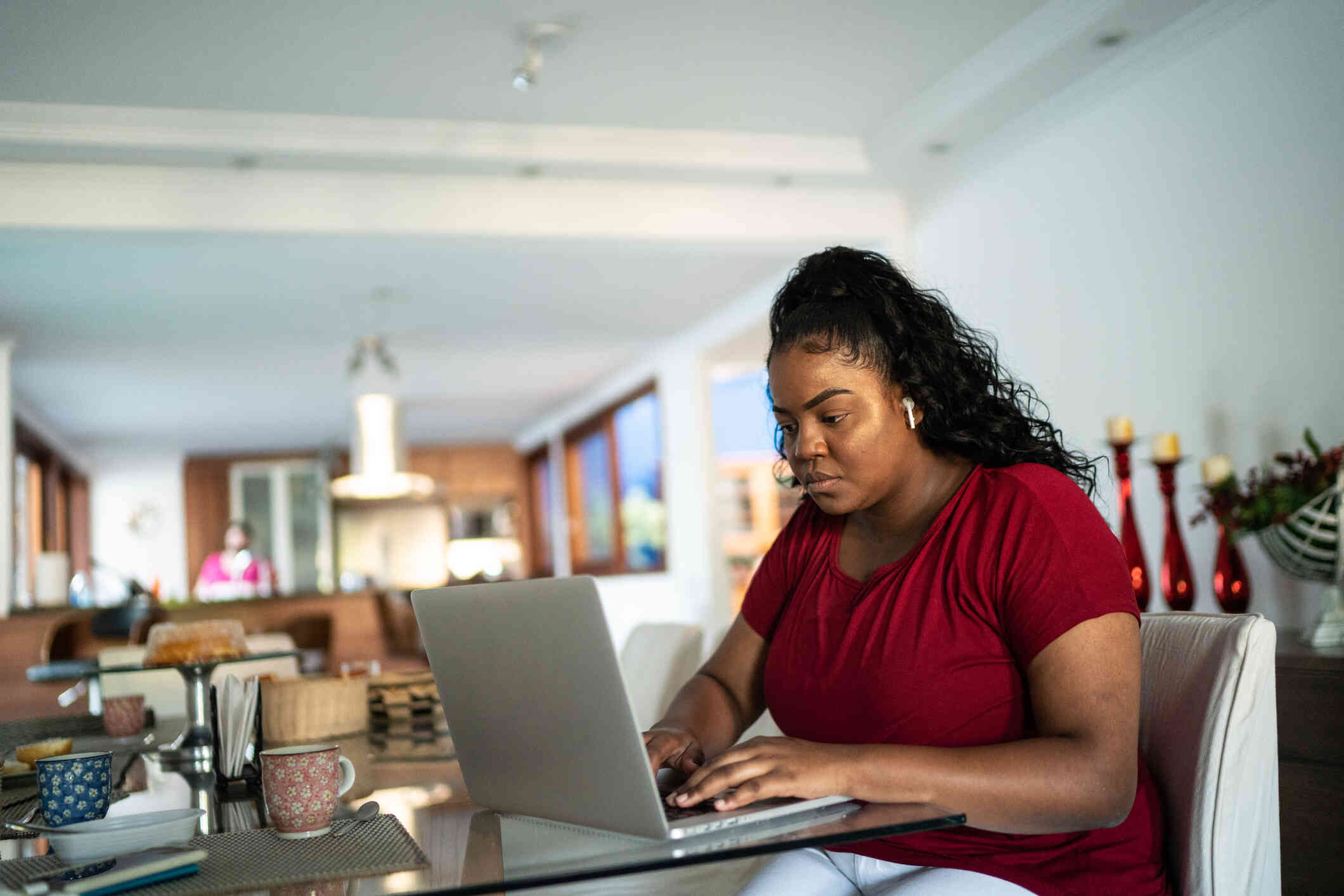 A woman seated at a table, busy typing on her laptop. 