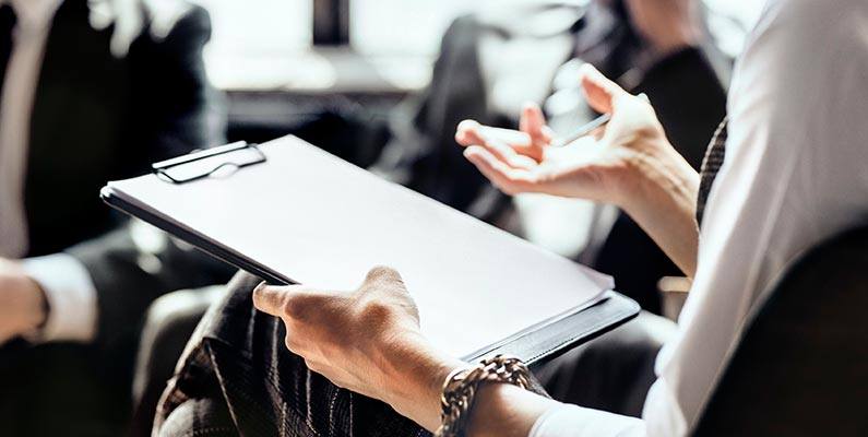 A close-up of a counselor holding a clipboard to take notes during a session with clients.